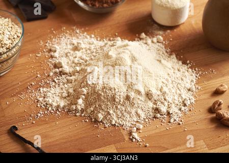 Flocons d'avoine moulus, poudre de protéines de lactosérum, vanille et beurre de noisette - ingrédients pour les barres de chocolat protéinées maison Banque D'Images