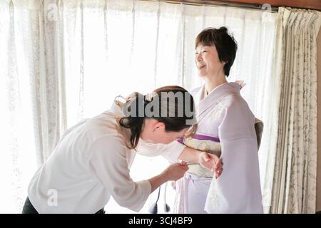 Une femme en kimono est aidée par une autre femme. La femme dans le kimono est souriante et elle est heureuse Banque D'Images