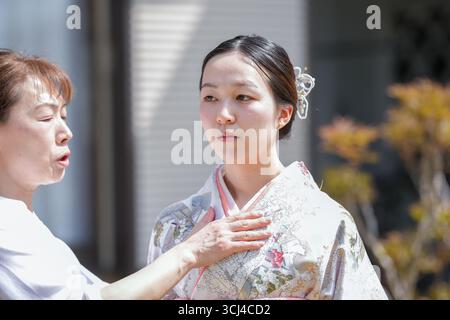 Une femme en kimono est aidée par une autre femme. La femme dans le kimono porte une chemise blanche sous son kimono Banque D'Images