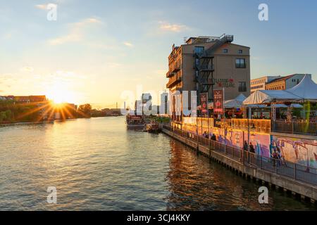 Berlin, Allemagne - 18 août 2025 : lumière de l'heure d'or se reflétant sur la rivière Spree, mettant en vedette des bâtiments urbains et des bateaux amarrés à Berlin. Banque D'Images