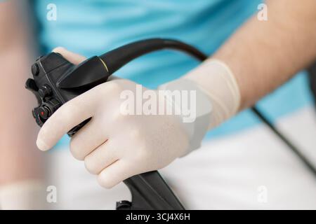 Un professionnel de la santé qualifié en gants saisit un endoscope, prêt à effectuer une procédure diagnostique cruciale dans un cadre clinique moderne. Banque D'Images