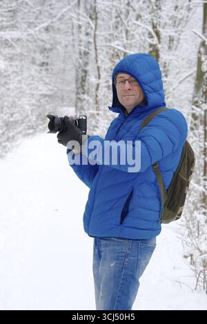 Caméraman professionnel avec caméra prenant des photos dans la forêt de neige Banque D'Images