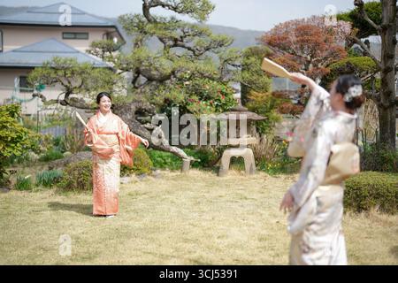 Deux femmes en kimonos jouant au badminton. Une des femmes tient une raquette Banque D'Images