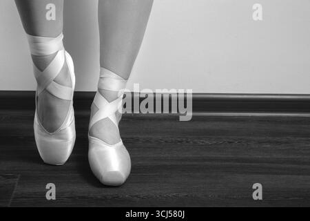 Pieds de ballerine femelle en pointes sur un plancher en bois gros plan image avec espace copie, monochrome Banque D'Images