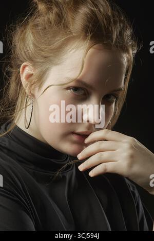 Jeune femme belle sérieuse regardant la caméra sur fond noir Banque D'Images