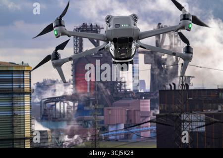 Image symbolique, photomontage, reconnaissance, espionnage avec des drones dans des installations industrielles, infrastructure critique, drone volant vers un industriel Banque D'Images