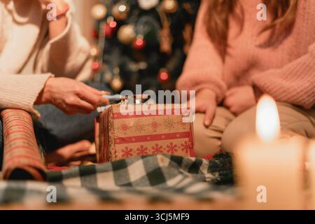 Une mère et sa fille s'assoient sur un canapé, partageant un moment réconfortant alors qu'elles tricotent ensemble. Cette image représente l'artisanat, la cohésion de la famille Banque D'Images