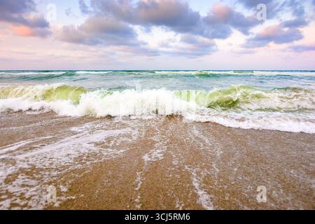 marée marine avant tempête. éclaboussure de vague avec de la mousse sur la plage de sable humide. temps venteux sur la saison du velours. fond de paysage marin spectaculaire Banque D'Images
