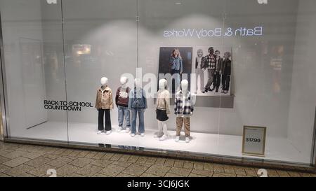 L'étui en verre présente plusieurs mannequins d'enfants dans une nouvelle collection dédiée à la saison scolaire, sur fond de deux affiches Banque D'Images