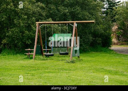 Balançoires en bois et table dans un parc naturel verdoyant avec un environnement tranquille. Banque D'Images