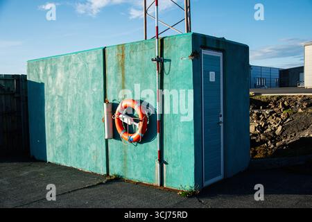 Structure turquoise avec bouée de sauvetage et porte dans un cadre extérieur en Islande. Banque D'Images
