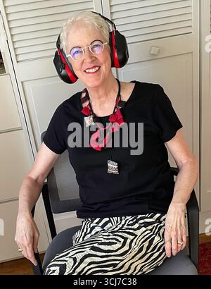 Portrait d'une femme âgée souriante, habillée à la mode, portant son casque antibruit assorti, 2025, New York City, États-Unis Banque D'Images