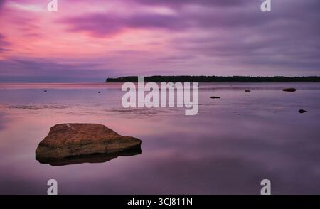 Coucher de soleil rose tranquille sur Rocky Shoreline Banque D'Images