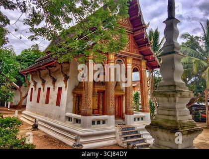 Temple bouddhiste orné et stupa à Wat Sen à Luang Prabang, Laos, entouré d'arbres tropicaux et de riches détails architecturaux.10 OCTOBRE 2017 Banque D'Images