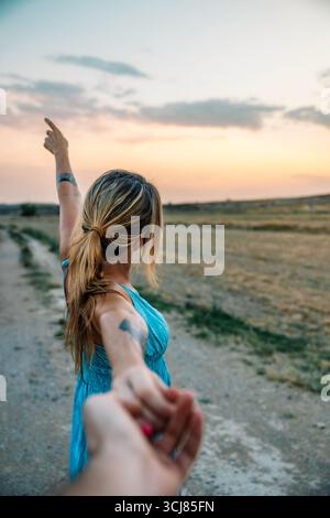 Femme partenaire principal à la main le long de la route de campagne au coucher du soleil Banque D'Images