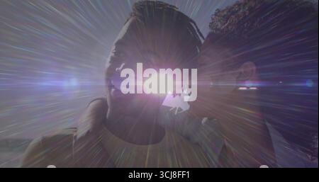 Couple souriant portant des hauts décontractés partageant un moment intime sur la vue côtière, avec des rayons de soleil Banque D'Images