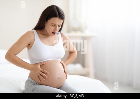 Femme enceinte souffrant de douleurs abdominales à la maison, espace de copie Banque D'Images