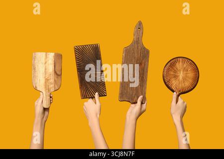 Mains féminines avec des planches à découper en bois sur fond jaune Banque D'Images