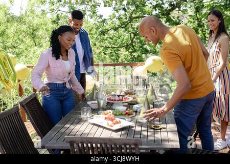 Amis appréciant la célébration d'anniversaire en plein air avec gâteau et décorations le jour ensoleillé Banque D'Images