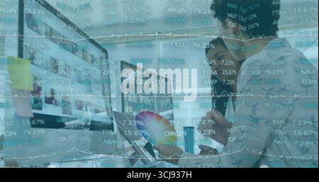 Deux collègues discutent des graphiques financiers sur des moniteurs dans un espace de bureau moderne, avec l'outil de roue de couleur Banque D'Images