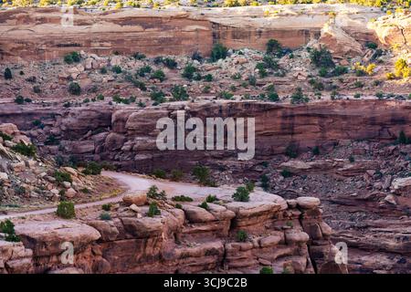 Un plan grand angle à couper le souffle capture un chemin de terre sinueux qui traverse un majestueux paysage de canyon de roches rouges, riche en formations géologiques stratifiées Banque D'Images