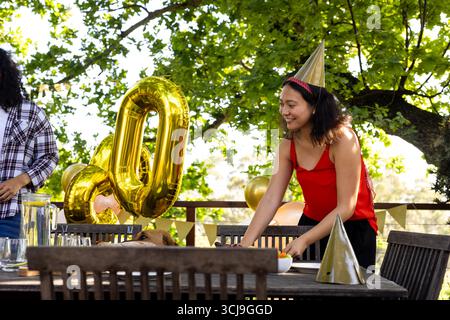 Table de mise à l'extérieur, femme en robe rouge organisant pour l'anniversaire avec des ballons Banque D'Images