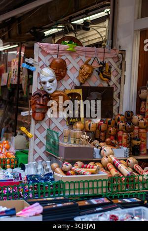 Vitrine de masques japonais traditionnels et de poupées kokeshi en bois sur un stand de marché de rue. Artisanat artisanal coloré et souvenirs culturels en vente. Banque D'Images