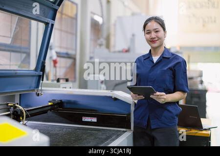 Heureux jeune technicien technicien ouvrier commande faire fonctionner la machine de découpe laser en métal dans l'usine moderne de l'industrie lourde en acier Banque D'Images