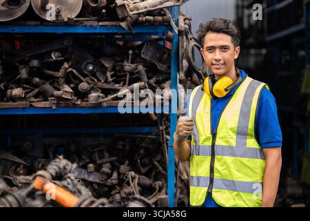 Ingénieur masculin asiatique confiant jeune travailleur debout pouces vers le haut sourire heureux pour profiter de travailler en usine Banque D'Images