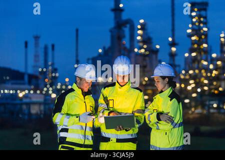 Groupe d'ingénieurs équipe de nuit travaillant le service de raffinerie de pétrole et de gaz, les travailleurs travaillent dur dans le fond d'usine de l'industrie pétrolière de nuit. Banque D'Images