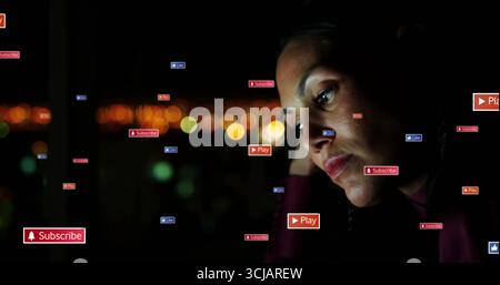 Femme au repos portant dessus sombre par fenêtre la nuit, icônes numériques flottantes, lumières de la ville, espace de copie Banque D'Images