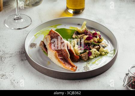 Bar grillé avec légumes et sauce verte Banque D'Images