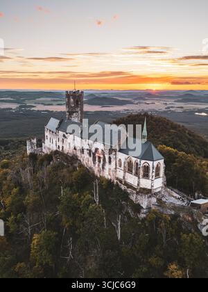 Le château de Bezdez se dresse fièrement au sommet d'une colline, baigné dans les teintes chaudes du coucher du soleil. Banque D'Images