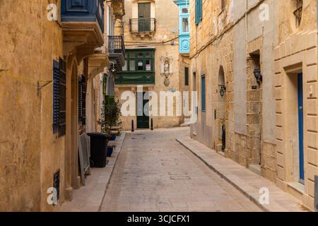 Birgu, Malte - 26 juin 2021 : ruelle en pierre étroite calme avec balcons colorés et portes traditionnelles dans la vieille ville. Banque D'Images