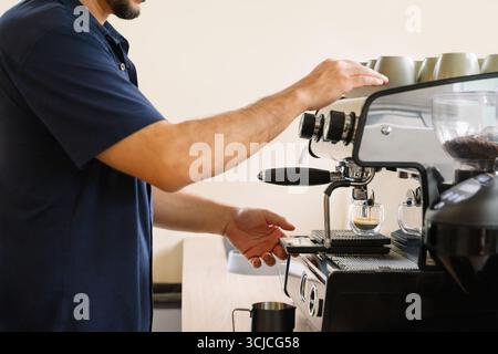 Un barista prépare le café avec compétence à l'aide d'une machine à espresso moderne, en soulignant la précision et le savoir-faire nécessaires pour créer une infusion parfaite, essentielle pour c Banque D'Images