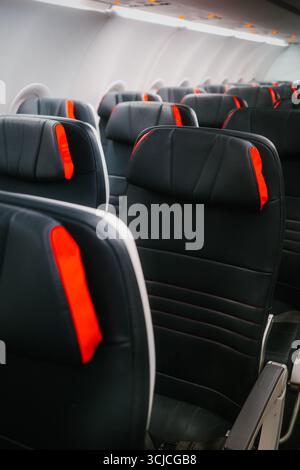 Vue sur les sièges modernes de l'avion avec sièges en cuir noir et touches rouges. L'arrangement illustre la conception confortable et élégante de l'avion trouvée dans c Banque D'Images