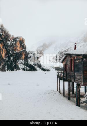 Paysage hivernal pittoresque dans les Dolomites, Italie, avec une cabine en bois confortable par une étendue enneigée. Les montagnes majestueuses s'élèvent abruptement, créant un Banque D'Images