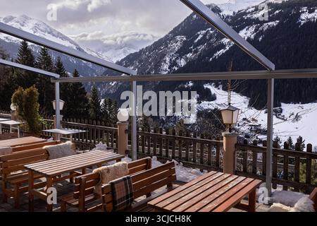 Un restaurant alpin serein en Autriche, doté de tables en bois et de touches chaleureuses, surplombe les montagnes enneigées. Parfait pour profiter de l'hiver » Banque D'Images