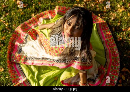 Une femme indienne brille dans un sari traditionnel vibrant, entouré de feuilles d'automne. Elle incarne l'élégance culturelle, se connectant profondément avec le tranqu de la nature Banque D'Images