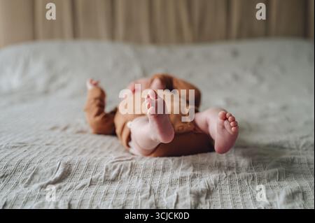 Un nouveau-né serein d'un mois couché paisiblement dans un cadre de lit confortable. Vêtu d'une douce combinaison, le bébé respire le confort et la chaleur dans une nurturin Banque D'Images