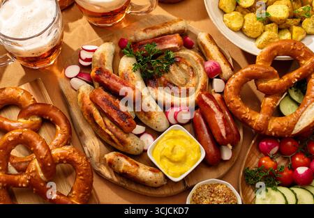 Vue de dessus d'un festin allemand avec diverses saucisses grillées, y compris Bratwurst et Frankfurter, entouré de bretzels fraîchement cuits, moutarde, pommes de terre Banque D'Images