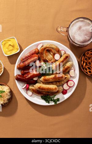 Vue de dessus d'un festin allemand avec des saucisses grillées, un grand bretzel et des radis sur une assiette. Accompagné de moutarde, choucroute, une tasse de bière, et p Banque D'Images