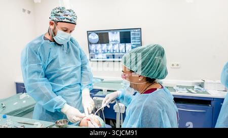 Un dentiste professionnel et un assistant effectuent une procédure d'implant dentaire dans une clinique moderne. Ils utilisent des outils et une technologie avancés pour assurer le highe Banque D'Images