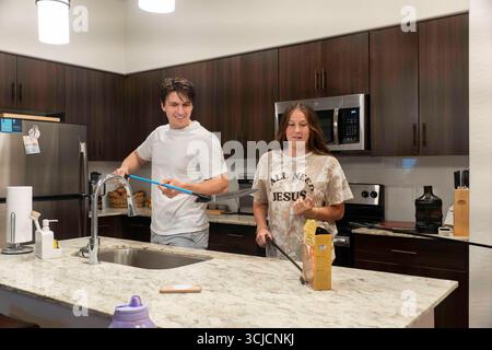 Un groupe de jeunes adultes appréciant cuisiner ensemble dans une cuisine moderne Banque D'Images