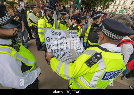 Londres, Royaume-Uni. 6 septembre 2025. Des policiers vêtus de vestes très visibles interagissent avec un manifestant tenant une pancarte lors d'une manifestation pro-palestinienne à Westminster. Le panneau indique arrêter le génocide en Palestine – L’action est obligatoire – Palestine action. La scène capture les tensions autour de l'activisme politique, de l'ordre public et de la liberté d'expression. Défendre nos jurys protestent contre la proscription de Palestine action avec plus de 1000 personnes faisant un engagement de tenir des signes au mépris de l'interdiction du Labour et montrant leur soutien au groupe interdit. Penelope Barritt/Alamy Live News Banque D'Images