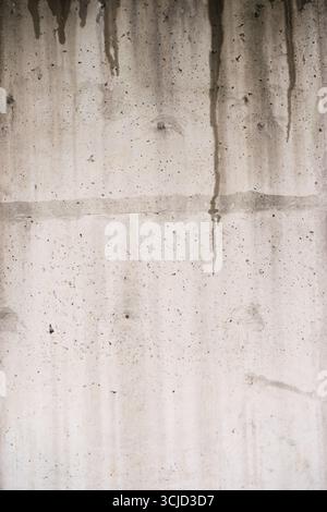 L'eau coule le long d'un mur de béton dur, créant un contraste saisissant avec les éclaboussures rouges éclatantes. Idéal pour les thèmes urbains et les visuels dramatiques Banque D'Images