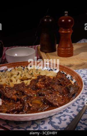 Délicieux goulash hongrois servi avec du spaetzle, créant un repas copieux et savoureux Banque D'Images