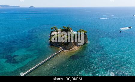 Vue aérienne de l'île de Cameo Zakynthos Grèce avec des eaux bleu cristal et turquoise pont en bois et bateaux naviguant autour de l'îlot pittoresque Banque D'Images