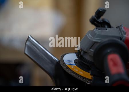 Meuleuse d'angle avec disque à lamelles sur bord métallique Banque D'Images