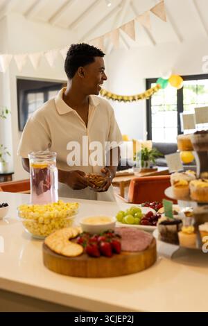 Homme appréciant des collations et des boissons à la maison pendant la célébration festive Banque D'Images